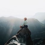 Sunrise Meditation - a man sitting on top of a large rock