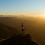 Yoga Nature - woman stretching on mountain top during sunrise